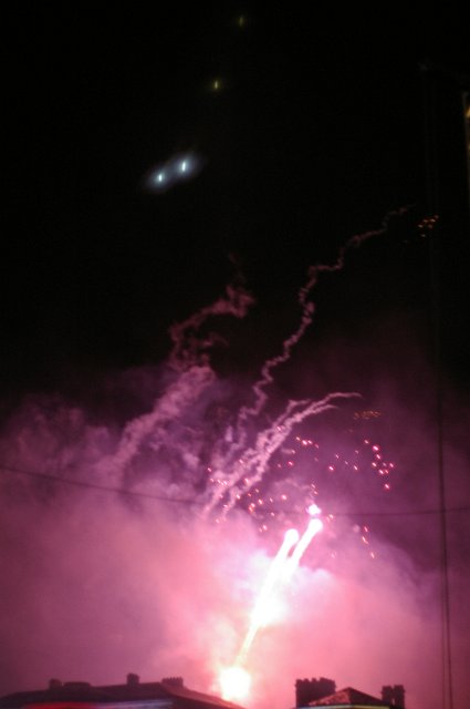 purple fireworks exploding above rooftops