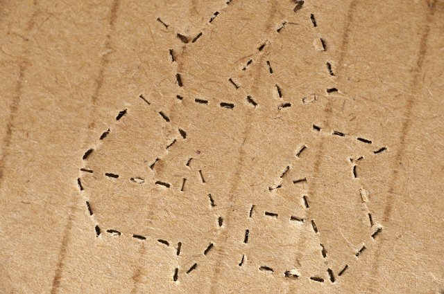Perforated recycle icon stamped on brown cardboard packaging in a close up view