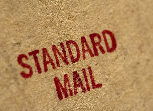 Standard Mail postage rate stamped in red on the side of a brown cardboard package , close up full frame texture background