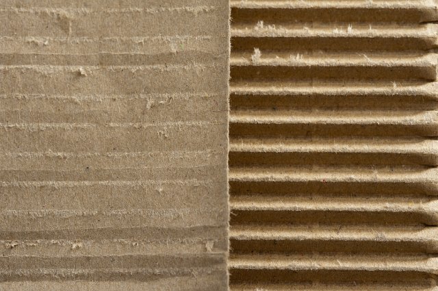 Two different textures of cardboard packaging, one with a smooth surface and one corrugated each in a half frame view