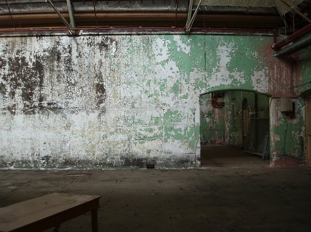 Old grunge gloomy warehouse interior with peeling paint and stains on the walls and damp stains near the floor