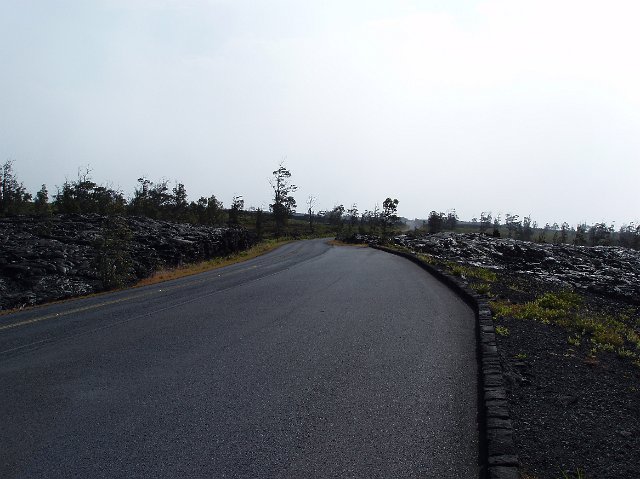 Unearthly dark moody atmospheric landscape under heavy grey cloud with a road winding away into the distance