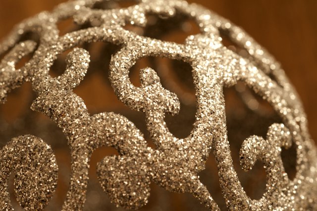 Close Up of Golden Glittering Christmas Ornament - Festive Holiday Ball with Intricate Heart Designs and Antique Feel