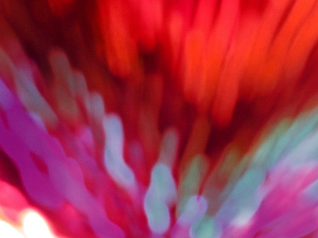 grainy motion blurred image with out of focus trails of light in mostly red and purple