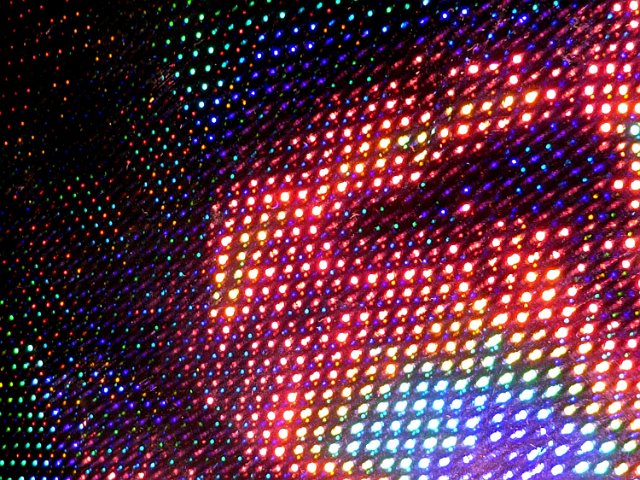 colourful pixels of light illuminated on a dark backdrop with noise and grain