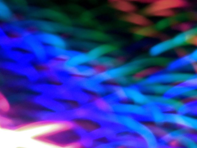 wave like traces of blue and other coloured lights on a dark background