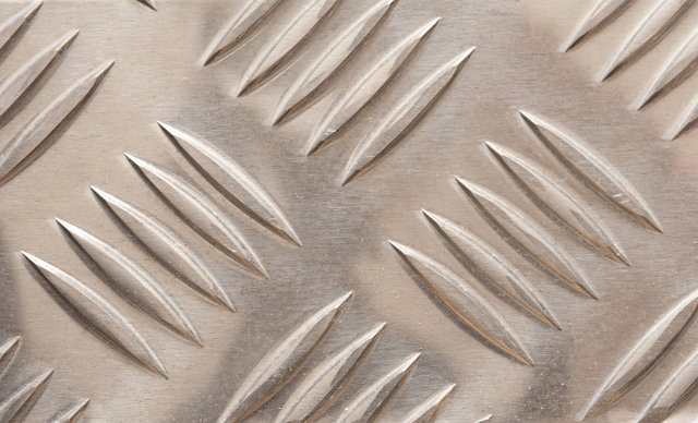 Industrial steel diamond plate with alternating incised checkered grid in a full frame background pattern and texture