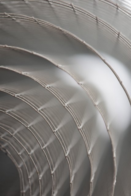 A close up of a coil of square gauge fencing wire with shallow depth of field.