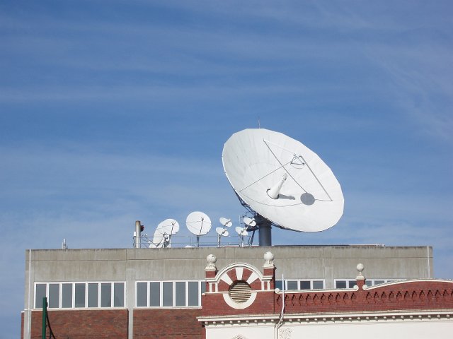 a large satellite dish mounted on a roof top with several other smaller dishes