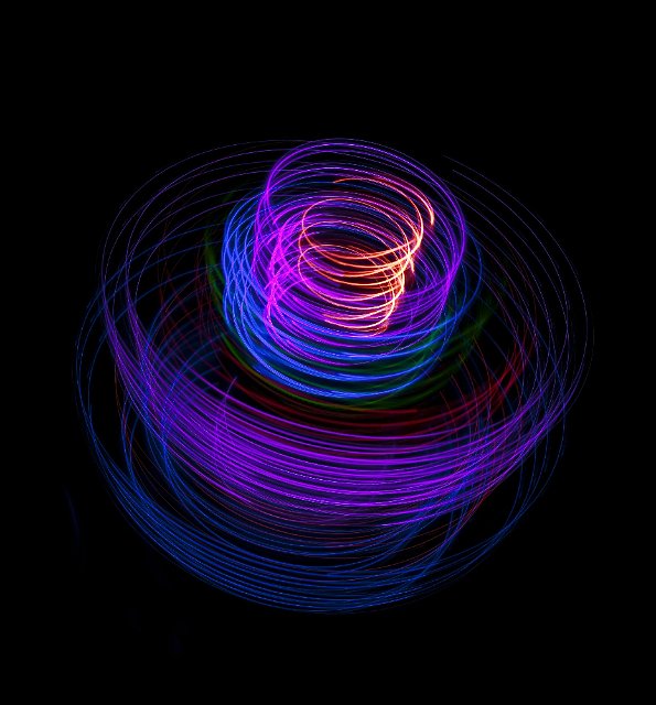 a glowing purple and pink coil of twisting light trails