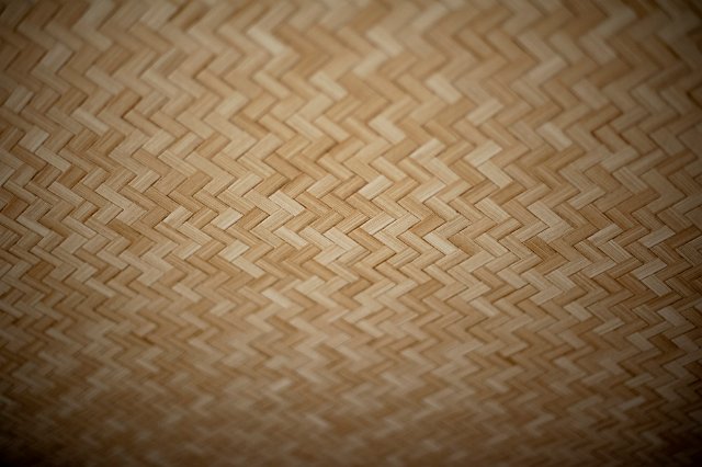 Background texture and repeat zigzag pattern of a woven bamboo ceiling with corner vignetting