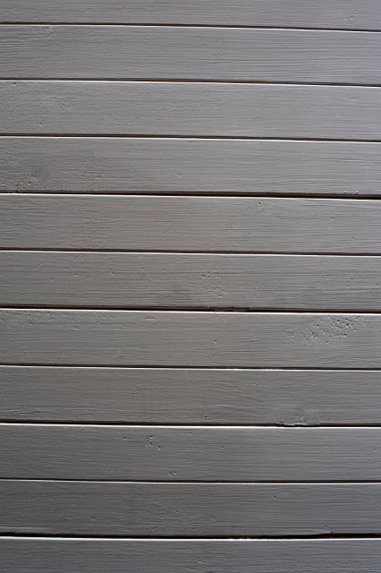 Horizontal wooden dado, or paneling decorating the lower half of an interior room in a building, painted in grey paint