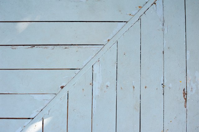 Corner of a wooden deck showing the right angle join between the planks and the background texture of the wood