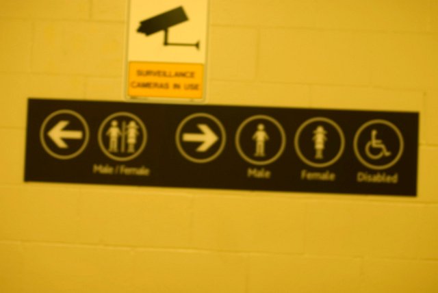 a defocused toilet sign on a concrete block wall