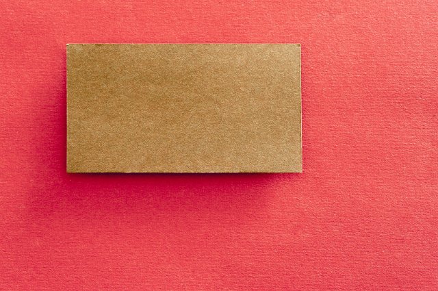 a brown wove paper label on red textured background - insert your own text